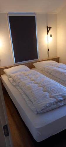 Una cama en un dormitorio con una ventana grande. en Rekerlanden 241, en Schoorldam