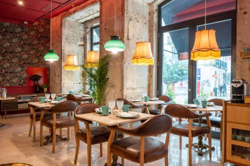 un restaurant avec des tables et des chaises en bois et de grandes fenêtres dans l'établissement Boemio FLH Hotels, à Lisbonne