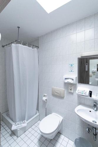 a white bathroom with a toilet and a sink at Taste Smart Hotel Backnang in Backnang