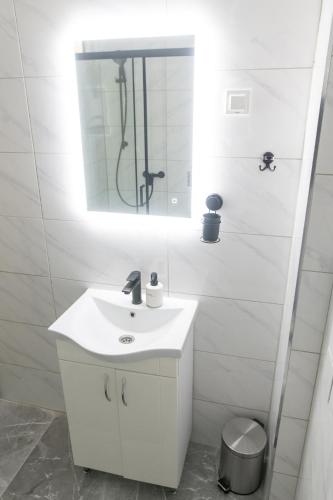 a white bathroom with a sink and a mirror at Apartman Škrinjar in Slavonski Brod