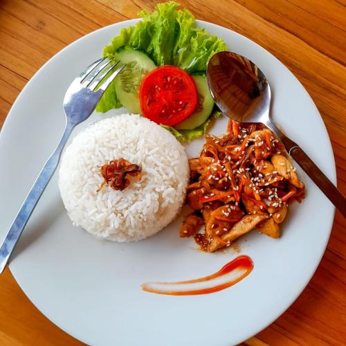a white plate of food with rice and vegetables at Griyatama Bungalow in Nusa Penida