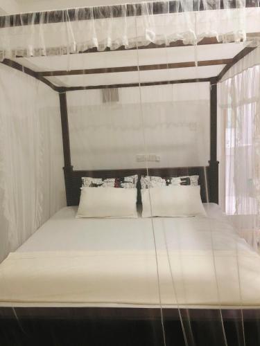 a canopy bed with white sheets and pillows at Amor Place Unawatuna in Unawatuna