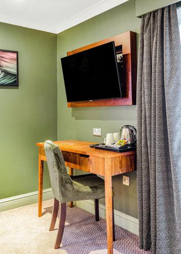 a wooden desk with a television and a chair at Inn on the Lake by Innkeeper's Collection in Godalming