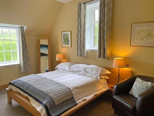 a bedroom with a bed and a chair and two windows at Glengorm Castle in Tobermory