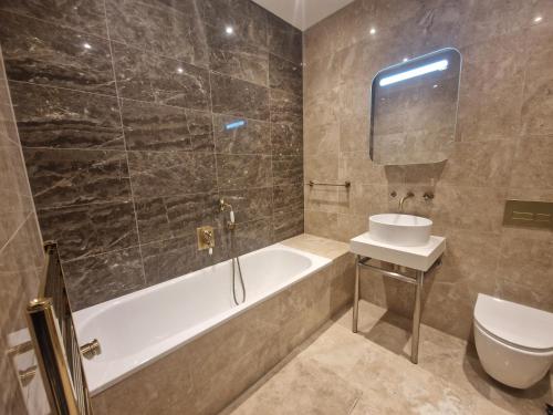 a bathroom with a tub and a toilet and a sink at Spacious 2 BR with Balcony in Hendon in Colindale