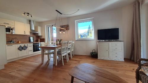 a kitchen and dining room with a table and a television at Ferienwohnung Edelbach Deluxe in Sattendorf
