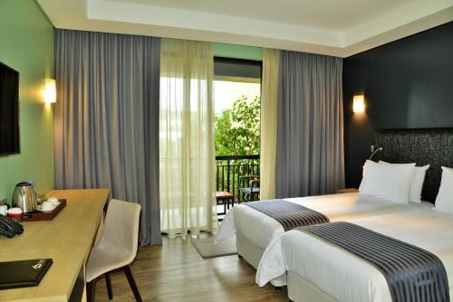Cette chambre comprend un lit, une table et un bureau. dans l'établissement EPIC Hotel & Suites, à Nyagatare