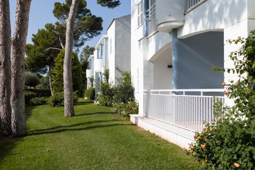 a side yard of a building with trees and grass at Sagitario Princesa Playa in Son Xoriguer