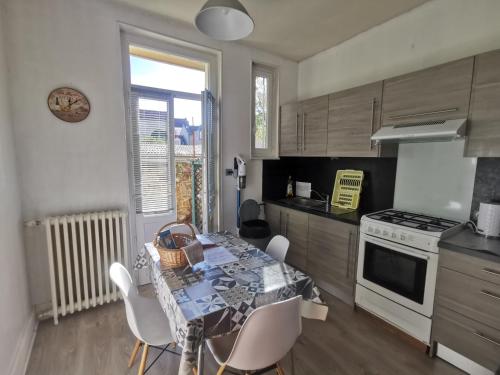 une cuisine avec une table, des chaises et une cuisinière dans l'établissement Bel appartement tout équipé! Proche des parcs, avec sa cour privative et sa place de parking sécurisée à 450 m du logement, à Vichy