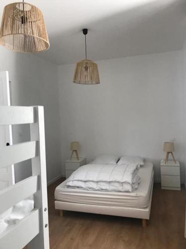een witte slaapkamer met 2 lampen en een bed bij Villa refaite à neuf à 200 mètres de la plage in Soulac-sur-Mer