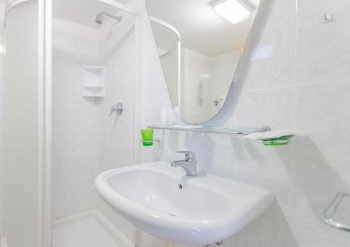 a white bathroom with a sink and a mirror at Hotel City in Misano Adriatico