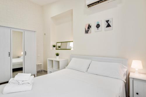 ein weißes Schlafzimmer mit einem weißen Bett und einem Spiegel in der Unterkunft Catania Modern Beige Apartment in Catania