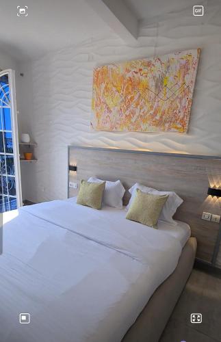 a bedroom with a large white bed with a painting on the wall at Dolce Vita Palacio in Douala