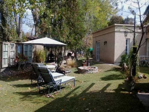 un patio trasero con mesa, sillas y sombrilla en Mendoza Leisure Time en Chacras de Coria