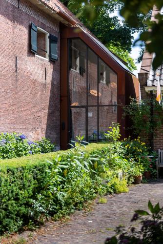 a brick building with a door and some bushes at Hotel Napoleonschuur in Amerongen