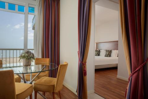 a dining room with a glass table and a bedroom at Savoia Hotel Rimini in Rimini