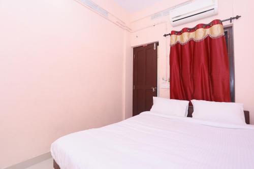 a bedroom with a white bed and a red curtain at PPG HOMES in Ernakulam