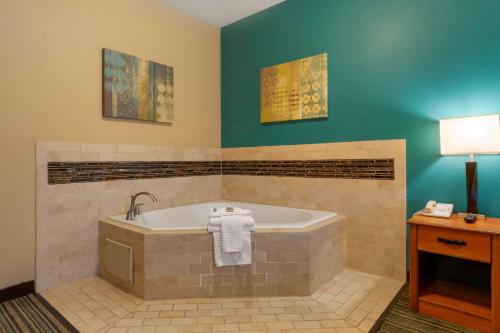 La salle de bains est pourvue d'une baignoire et d'une table avec une lampe. dans l'établissement Best Western Governors Inn and Suites, à Wichita