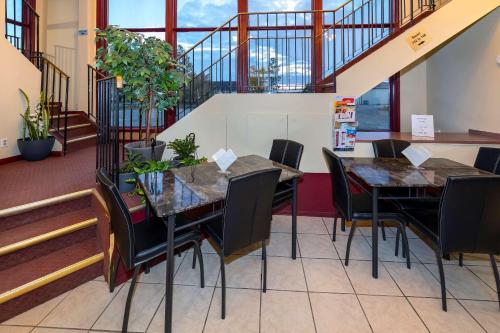 a dining room with two tables and chairs and stairs at Econolodge Edson in Edson