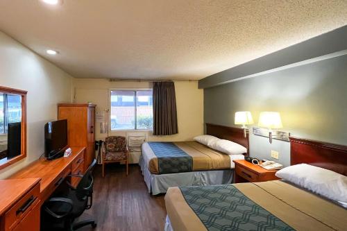 a hotel room with two beds and a television at Econo Lodge Motel Village in Calgary