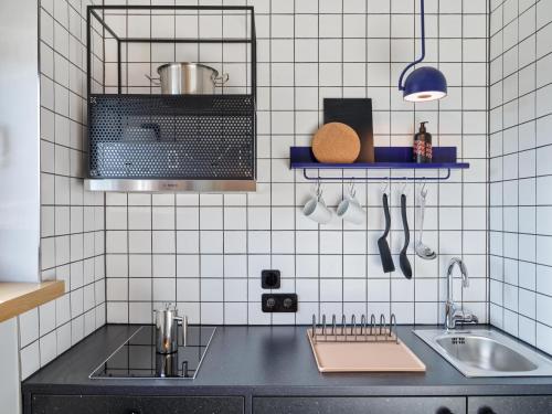 a kitchen with a sink and white tiled walls at STAYERY Wolfsburg City in Wolfsburg