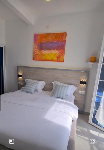 a bedroom with a white bed and a painting on the wall at Dolce Vita Palacio in Douala