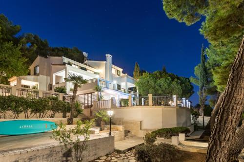 a large white house with a swimming pool in front of it at Apartments Croatia in Trogir