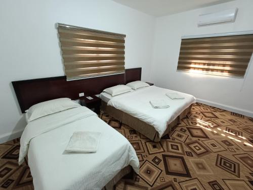 a hotel room with two beds and two windows at Happy Night Hostel in Wadi Musa