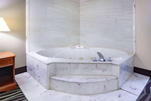 eine weiße Badewanne in einem Zimmer mit einem Tisch in der Unterkunft Travelodge by Wyndham Monroe in Monroe