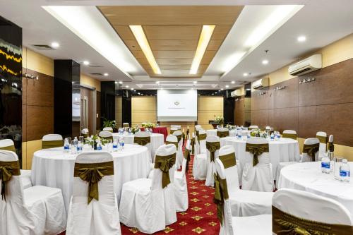 a banquet hall with white tables and chairs and a screen at Bao Son International Hotel in Hanoi