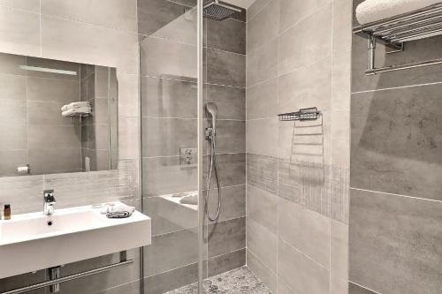 y baño con ducha y lavamanos. en Grand Hôtel des Bains SPA, en Fouras