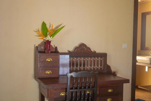 a wooden desk with a vase of flowers on it at Guru Beach Resort in Tangalle