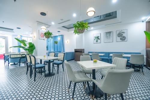 a restaurant with white tables and blue chairs at Bao Son International Hotel in Hanoi