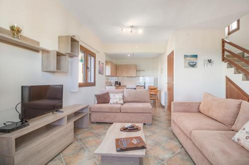 ein Wohnzimmer mit einem Sofa und einem TV in der Unterkunft Seaview Villas in Vourvourou