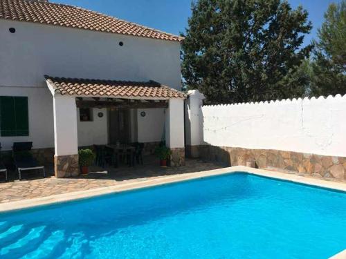 a blue swimming pool in front of a white house at Cortijo La Gineta in Alcalá la Real