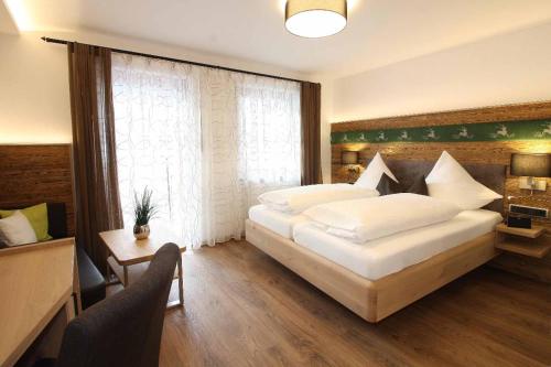 a bedroom with a large white bed and a window at Landhotel Kleblmühle in Grafenau