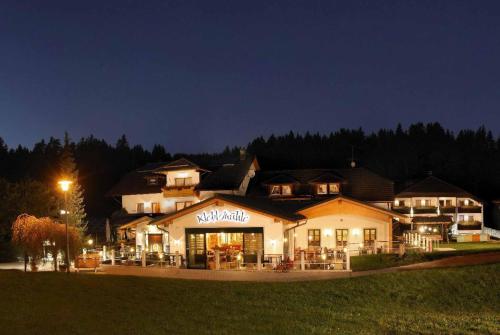 a large building with a restaurant at night at Landhotel Kleblmühle in Grafenau