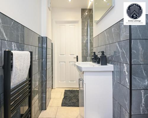 a bathroom with a white sink and black tiles at SPECIAL PROMO! Perfect Group Accommodation, 3 Bathrooms Perfect for Contractors and Businesses with relocation Requirement near Harwich Sea Port in Harwich