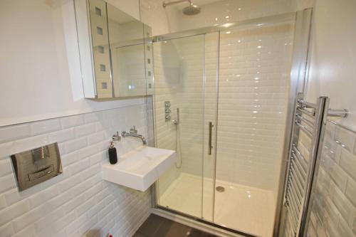 ein weißes Badezimmer mit Waschbecken und Dusche in der Unterkunft Modern Home for Small Groups by Stones Throw Apartments - Free Parking - Sea View in Worthing