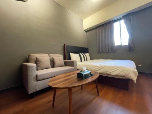 1 dormitorio con cama, sofá y mesa en 一中自在居 en Taichung