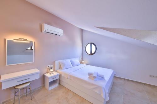 a white bedroom with a white bed and a desk at James Pansiyon Blue sea view villas Kaş Peninsula in Kas
