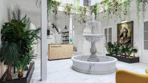 a fountain in the middle of a room with plants at Planeta Cadiz Hostel in Cádiz