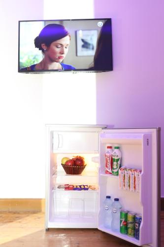a small refrigerator with its door open with a tv above it at New Midtown in Cairo