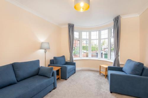 a living room with two blue couches and a window at Five Bedroom Holiday House York Centre - Peace house in York