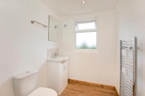 a white bathroom with a toilet and a window at Five Bedroom Holiday House York Centre - Peace house in York