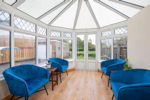 a conservatory with blue chairs and windows at Five Bedroom Holiday House York Centre - Peace house in York
