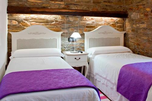 a bedroom with two beds with purple and white sheets at Casas Rurales TAReira en Taramundi in Taramundi