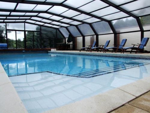 a large swimming pool with blue chairs in it at Valley View Lodge in Welshpool