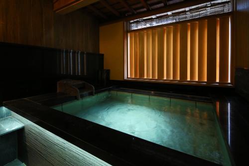 a hot tub in a room with a window at Ichidaya in Toyooka