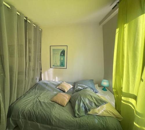 a bedroom with a bed with green sheets and pillows at charmant studio sous les toits de Paris in Paris